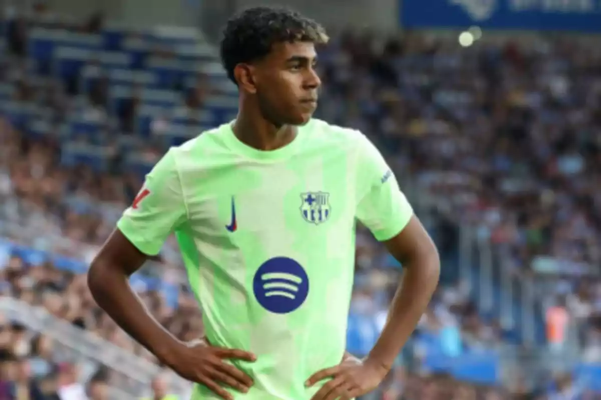 Football player in a light green jersey in a stadium during a match.