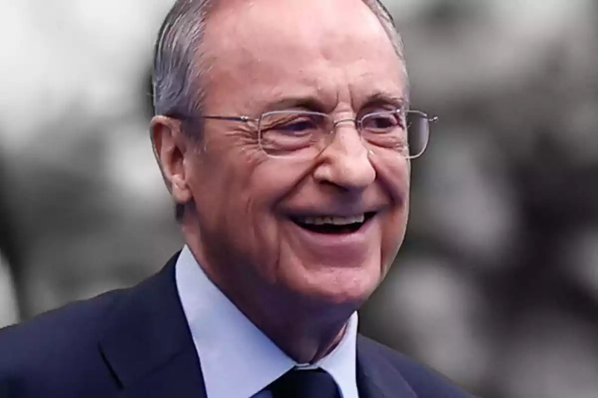 Older man with glasses and suit smiling.