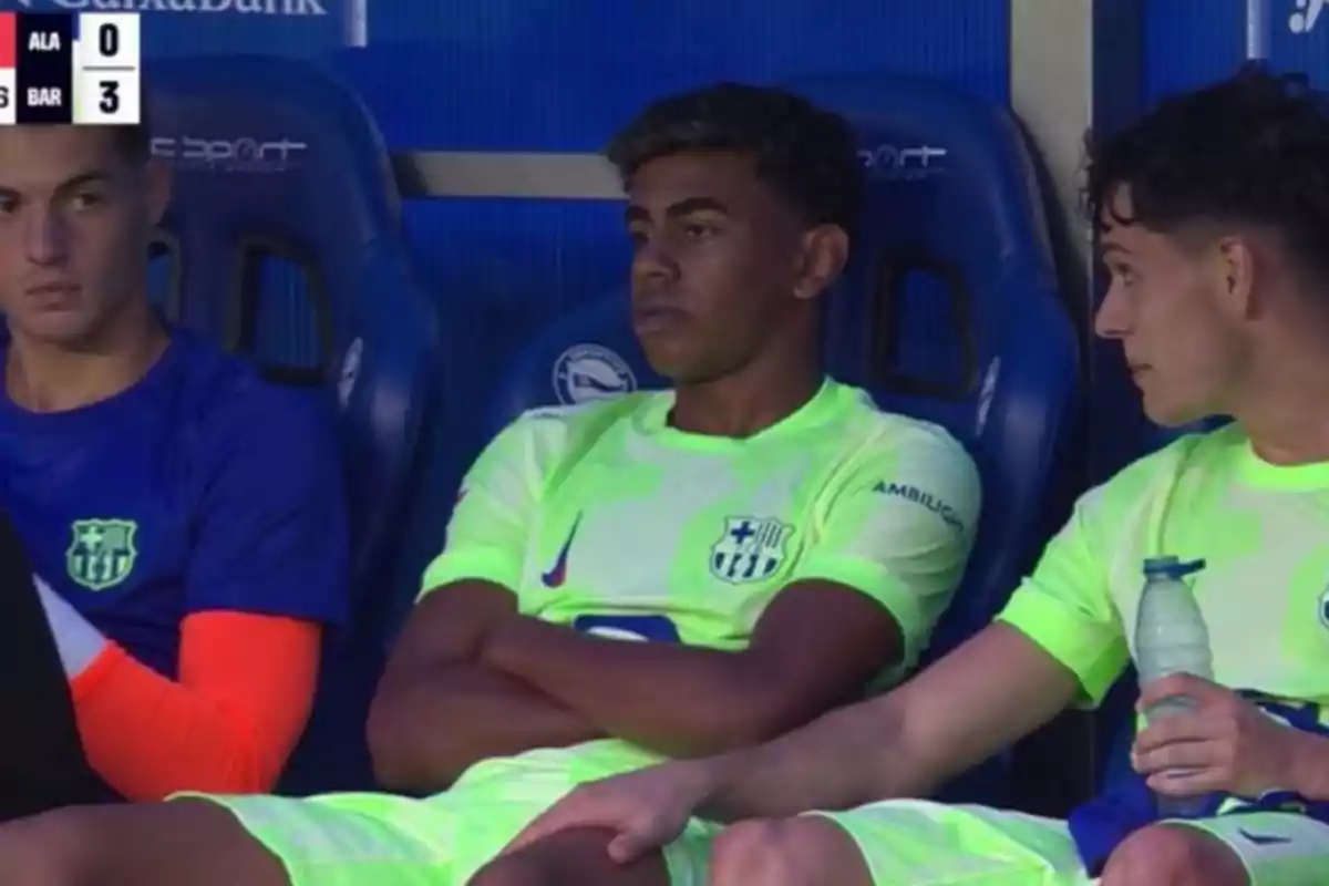 Players sitting on the bench during a football match with scoreboard showing Alaves 0 and Barcelona 3.