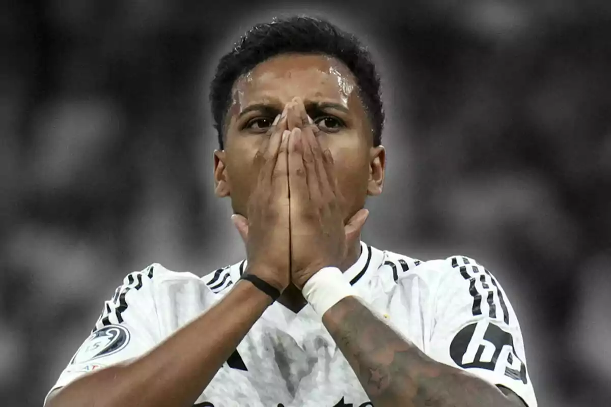 Rodrygo Goes with a surprised or worried expression, wearing a black and white uniform, with his hands together in front of his face.